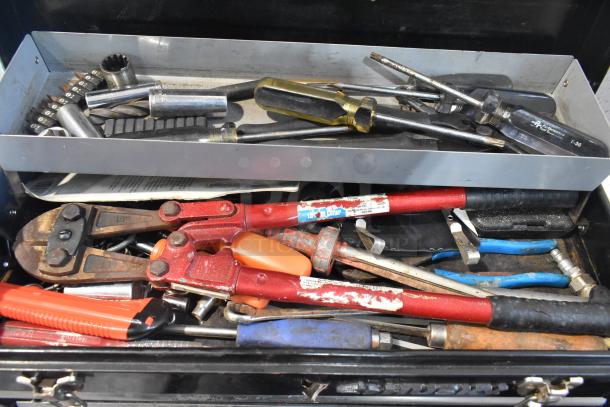 Husky black metal toolbox with assorted tools, including wrenches and screwdrivers. Visible wear, ideal for DIY enthusiasts.