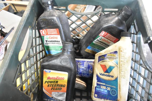 Assorted automotive fluid bottles including Castrol Transmax, AutoZone Power Steering Fluid, and Valvoline Motor Oil in a crate.