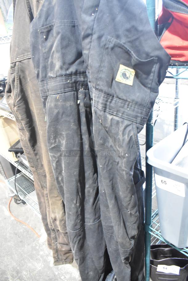 Alt text: Blue Carhartt overalls with a visible logo patch, hanging on a rack. They appear lightly worn.