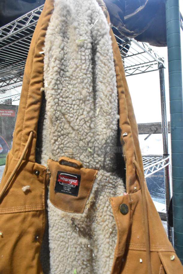 Alt Text: Brown overalls with fleece lining, featuring a visible Wrangler tag, part of a mixed auction lot.