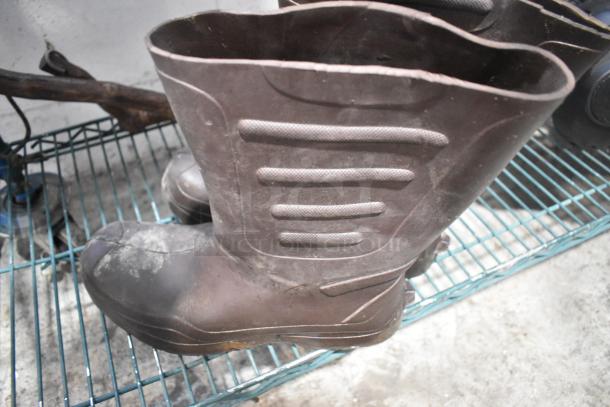 Tier lot featuring brown rubber boots, scuffed condition, on metal shelf. Includes unspecified speaker and hitch components.