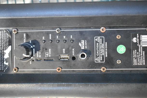 Portable speaker control panel with volume knob, TF card, USB, and AUX inputs. Caution label indicates risk of electric shock.