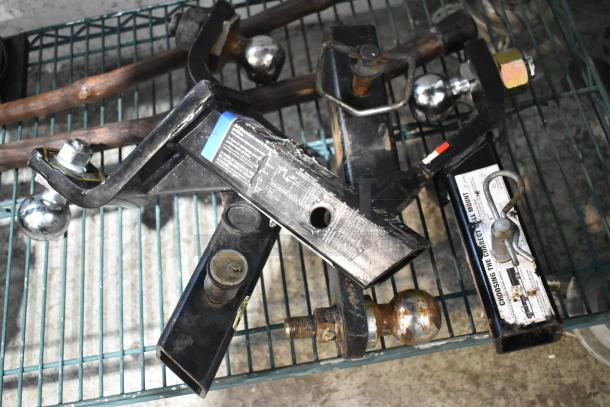 Tiered lot including various hitches with ball mounts and labels. Items show signs of wear, suitable for automotive use.