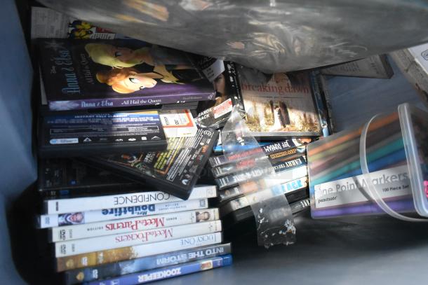 Tiered lot of various items including DVDs, markers, and tools. Visible are DVDs of "Anna & Elsa" and "Breaking Dawn," plus a 100-piece marker set.