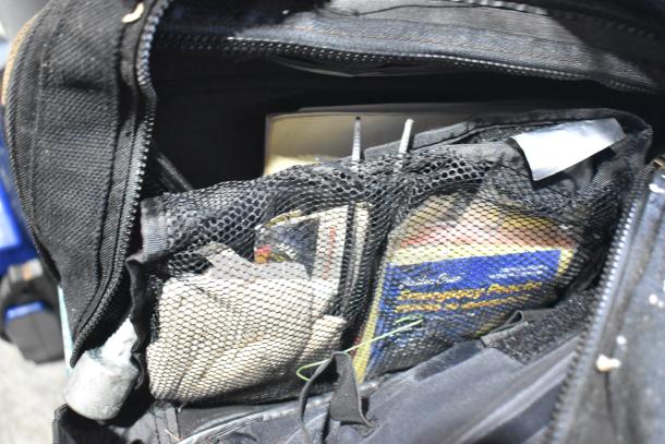 Bag containing a portable DVD player, DVDs, markers, tools, and an Amerex fire extinguisher. Items visible through mesh pockets.