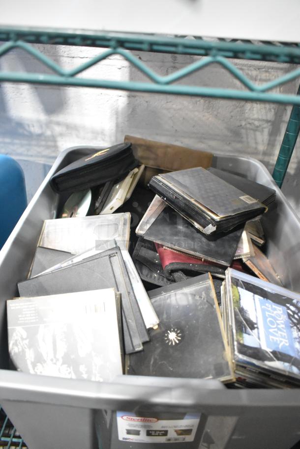 Tiered lot of various items including portable DVD player, DVDs, markers, tools, and Amerex fire extinguisher in a storage bin.