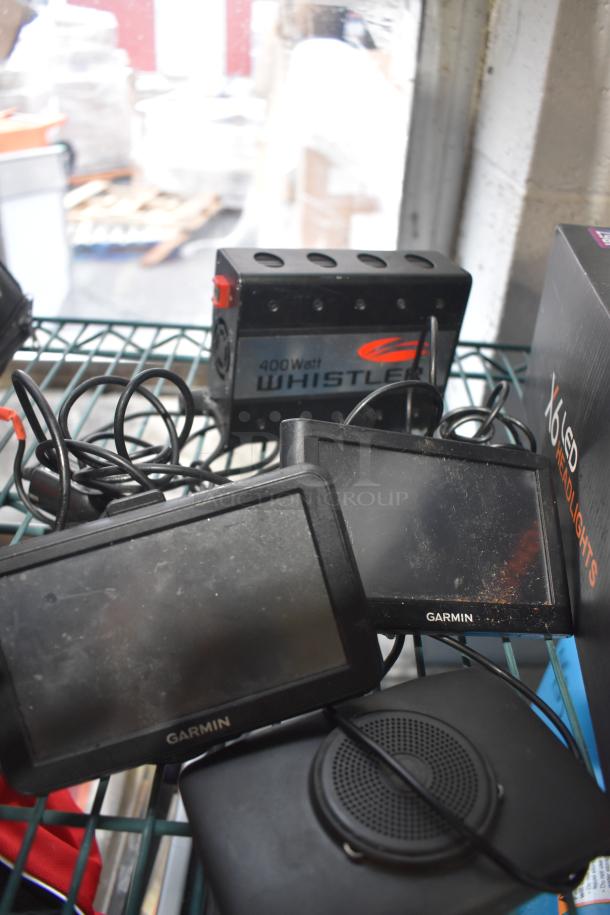 alt text: Assorted auction items including Garmin GPS units, Whistler 400 Watt device, and X6 LED Headlights box.