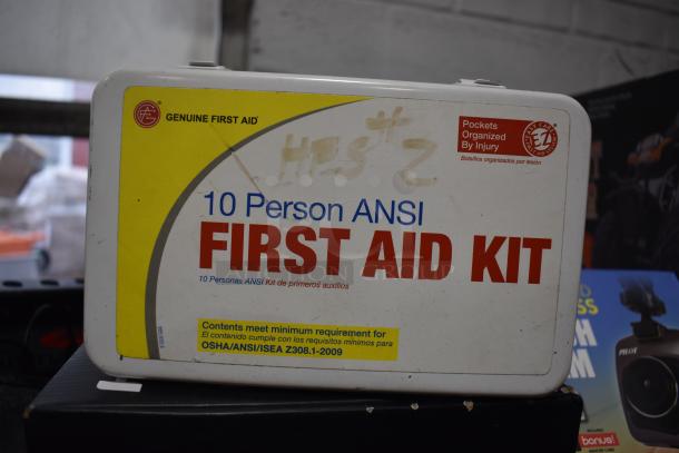 "Genuine First Aid 10 Person ANSI First Aid Kit, white and yellow with compliance labels, minor wear visible."