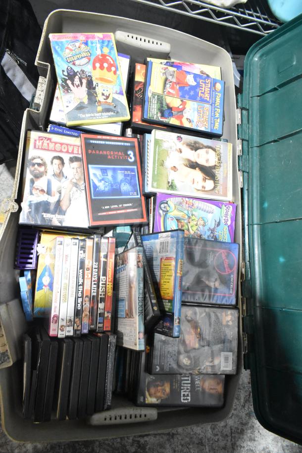 Lot of DVDs in a poly bin, including titles like "The SpongeBob SquarePants Movie" and "Paranormal Activity 3."