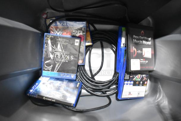 Tier lot of items in a poly bin, including PS4 games like Skyrim and WWE 2K, power cables, and a GameStop card case.