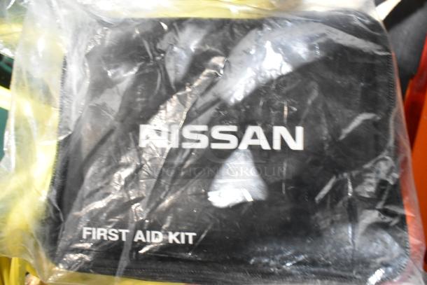 Nissan first aid kit in original packaging, part of tier lot including jumper cables, tools, and rainsuit.