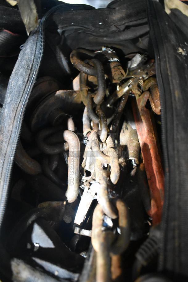 Tier lot of tools including jumper cables and chains, showing signs of rust and wear. Black zip-up bag included.