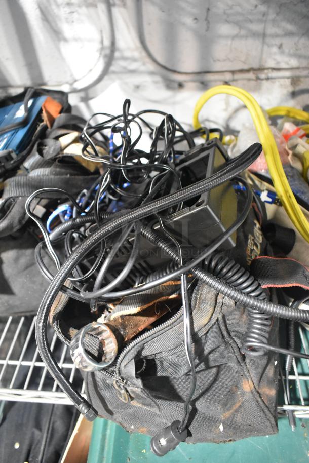 Tier lot including assorted cables, tools, jumper cables, and rainsuit. Items are tangled, showing wear and rust.