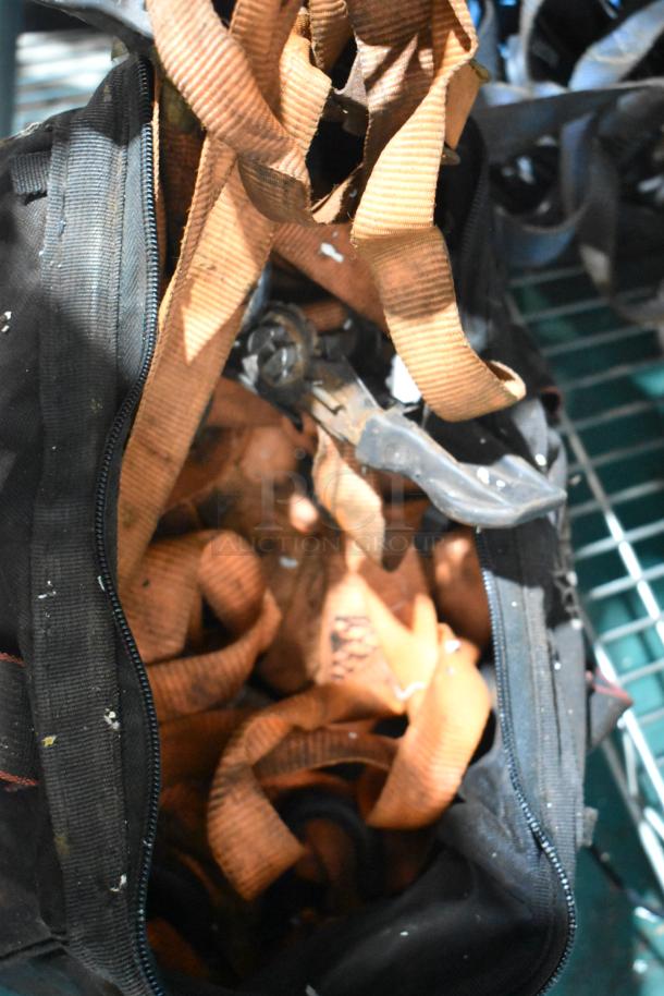 Auction lot with a variety of items including orange straps in a black bag. Condition shows signs of use.