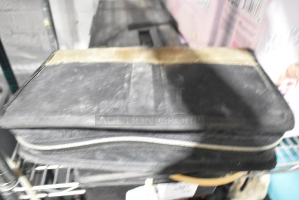 A blurry image of a black rectangular bag with zippers; part of an auction lot including CDs, a unicorn tent, a Jeep bag, and a Westward power source.