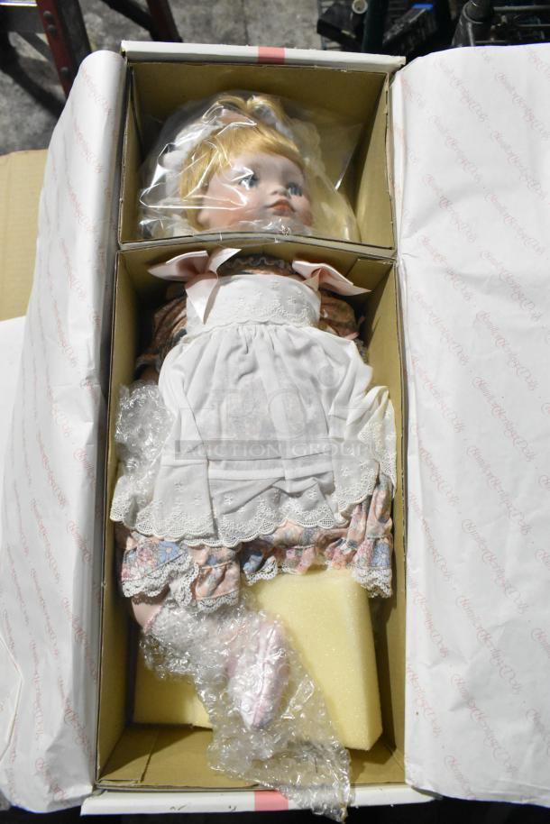 Boxed collectible doll with blonde hair, dressed in lace-trimmed clothes. Original packaging "Collectible Heritage Dolls" visible.