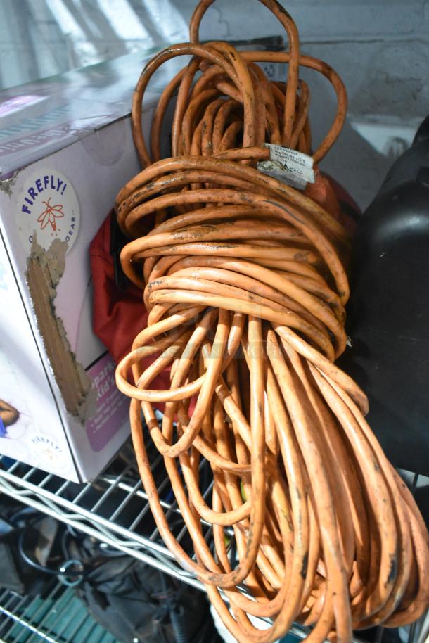 Coiled orange extension cord on a shelf, with part of a Firefly unicorn tent package visible nearby.