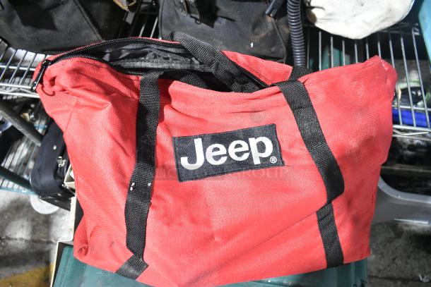 Red Jeep bag with black handles and logo, part of auction tier lot including CDs, unicorn tent, and Westward power source.