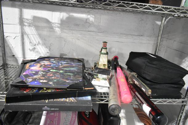 Mixed lot with baseball bats, a Black Panther poster, lighthouse fixture, and other items on a metal shelf. Items vary in condition.
