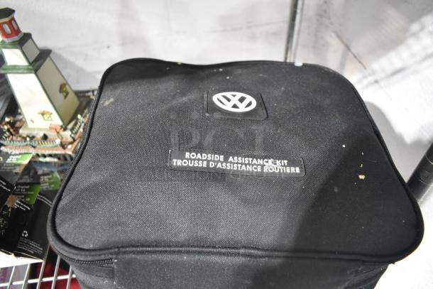 Volkswagen Roadside Assistance Kit with logo, black fabric case. Includes items like a lighthouse fixture and Black Panther poster.