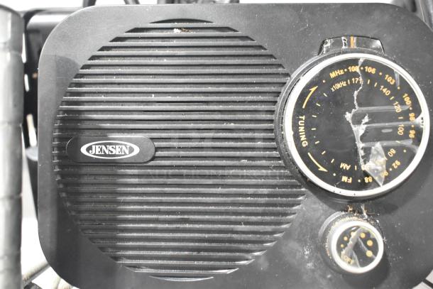 Vintage Jensen radio with tuning knob and frequency markings, in worn condition with visible scratches on the dial cover.