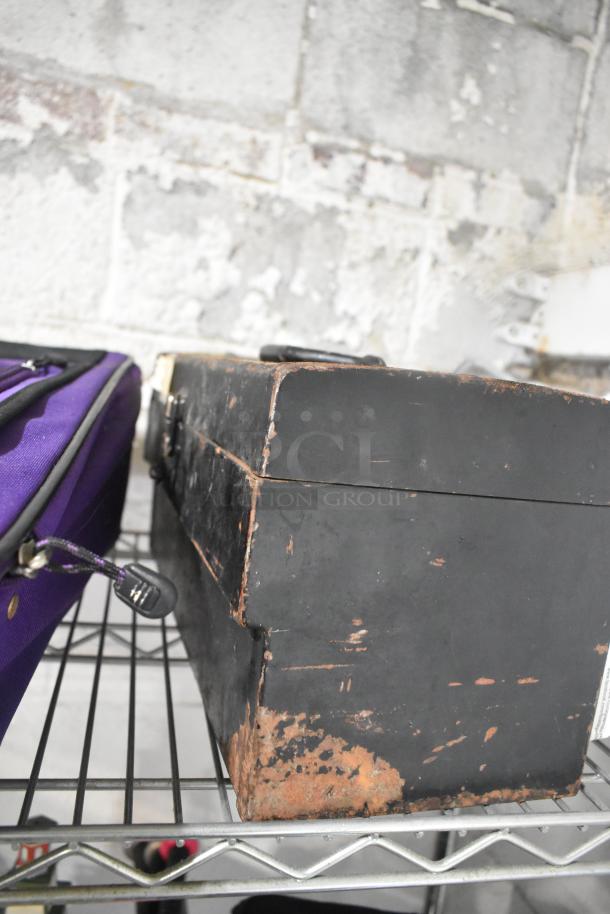 Lot of items featuring a purple suitcase and a vintage black toolbox with rust and wear, highlighting a rustic charm.