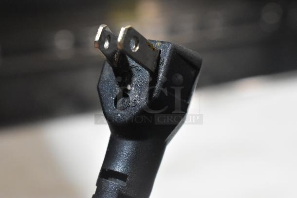 Close-up image of a two-prong electrical plug, showing some wear and surface marks.