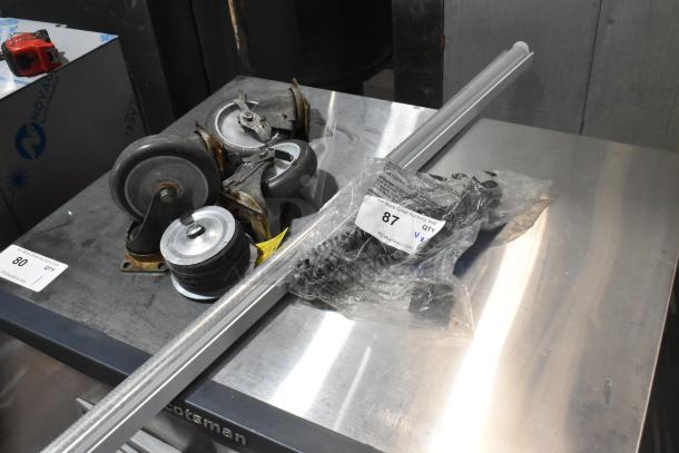 Lot of 7 items; includes 4 casters and a vacuum brush. Casters in used condition. Bag labeled "87" with parts.