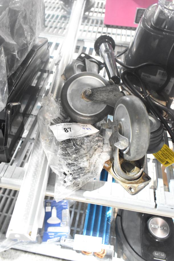 Lot of 7 items including 4 industrial casters and a vacuum brush, minor wear. Includes auction tag labeled "87 V1".