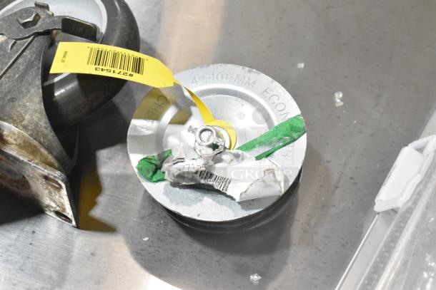 Lot of 7 items including 4 casters, one labeled "44-100MM ECONOMY," and a vacuum brush. Items show wear, some with tags.