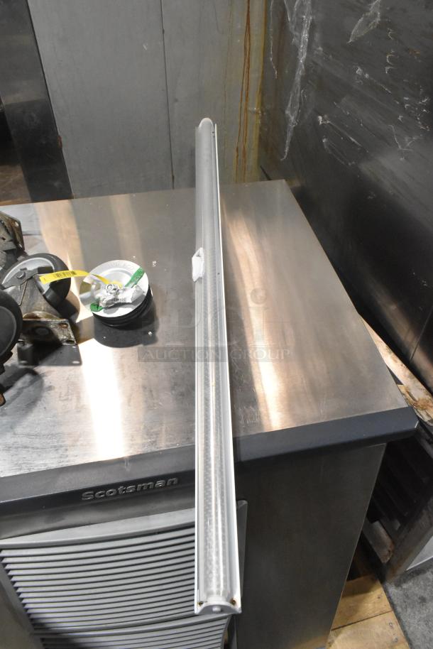 Lot of 7 items including 4 casters and a vacuum brush on metal surface. Includes linear light fixture, Scotsman label visible.