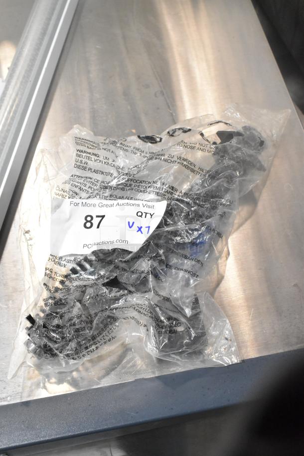 Bag containing a lot of 7 items, including 4 casters and a vacuum brush, in new condition with auction tag "87".