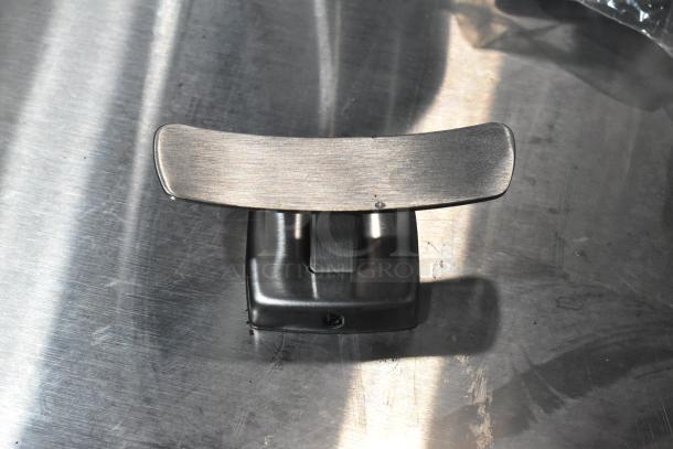 Metallic object, possibly a component of the Advantage Supplies 158ADVHDB hand dryer, set on a reflective metal surface.