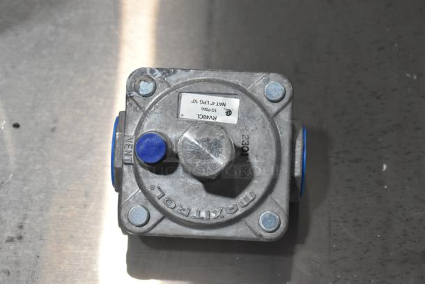 Metal component with blue caps and "Maxitrol" label, showing vent marking. Appears in used condition.