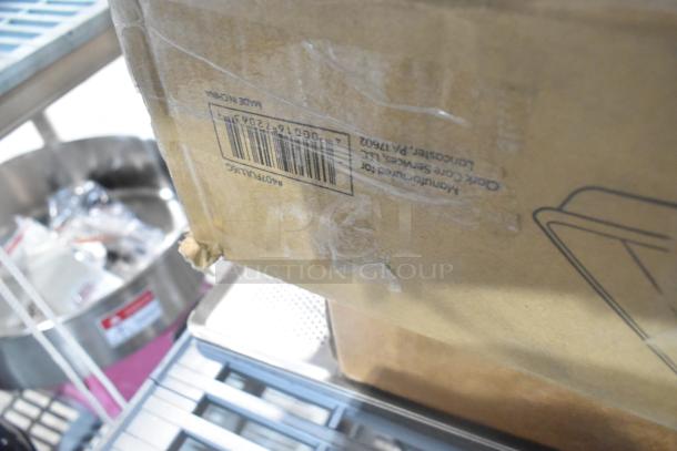 Cardboard box showing barcode and "Made in China" label, containing brand new scratch and dent slate trays and sheet pans.