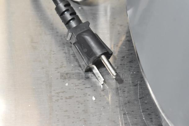 Close-up of a black power plug for the AvaMix 928BL2K64 2 hp Commercial Blender, shown on a metallic surface.