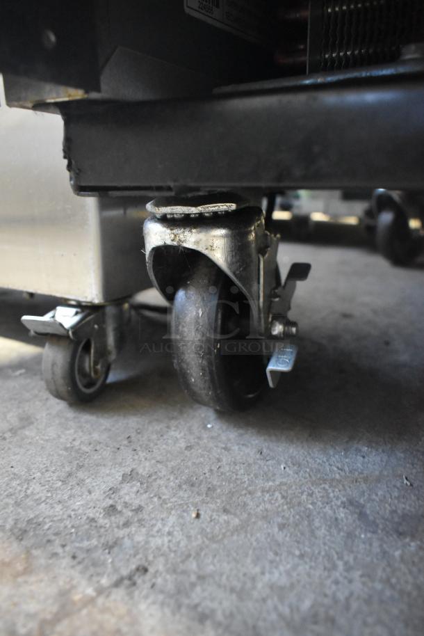 Casters of a 2023 True T-23F-HC commercial freezer, showing poly-coated racks and stainless steel exterior.