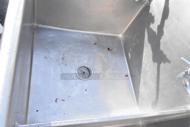 Stainless steel 3-bay sink with right side drain board, features two faucets and handles, visible wear and debris in basin.