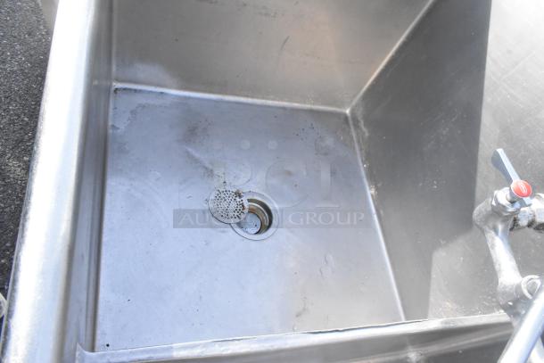 Stainless steel 3 bay sink with right side drain board, featuring 2 faucets and handles. Signs of use visible.