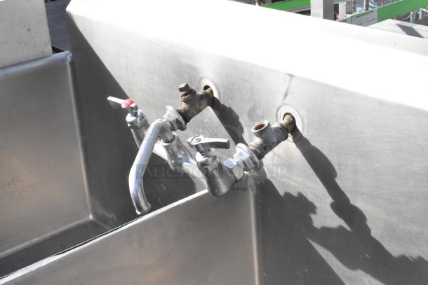 Stainless steel 3 bay sink with right side drain board, featuring two faucets and handles in good condition.