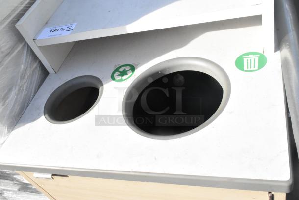 Commercial trash receptacle with deposit holes, tray slide, and door. Features recycle and trash symbols.