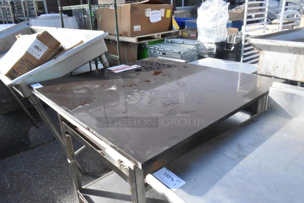 Metal table with under shelf in used condition. Sturdy design, metallic finish, suitable for storage and kitchen use.