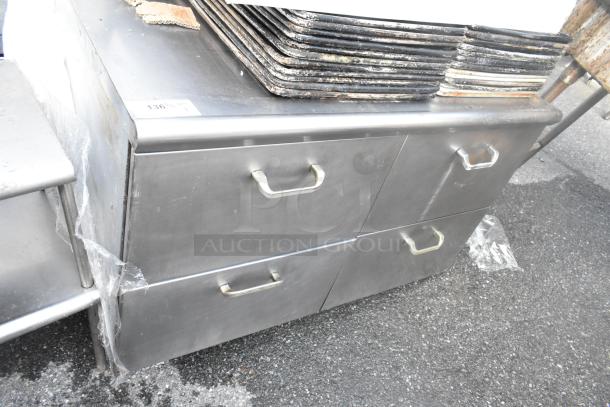 Stainless steel 4-drawer counter, durable design, visible wear, sturdy handles, ideal for kitchen or industrial use.