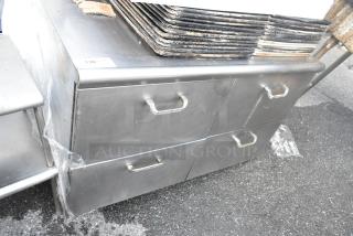 Stainless steel 4-drawer counter, durable design, visible wear, sturdy handles, ideal for kitchen or industrial use.