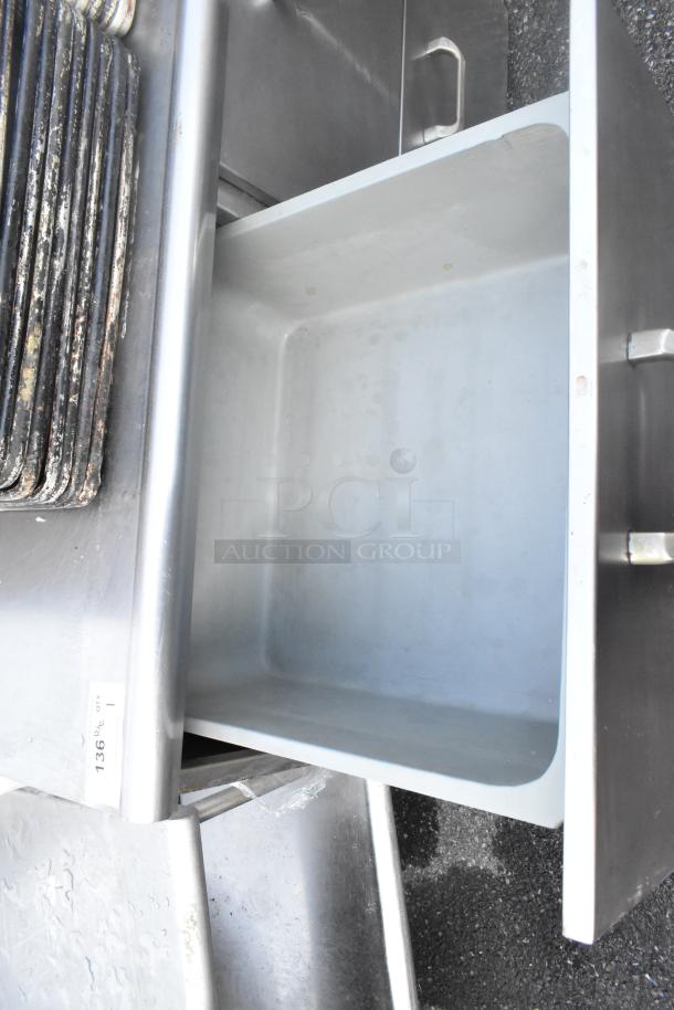 Stainless steel 4-drawer counter, visible open drawer, robust handles, slight wear marks, ideal for kitchen storage.