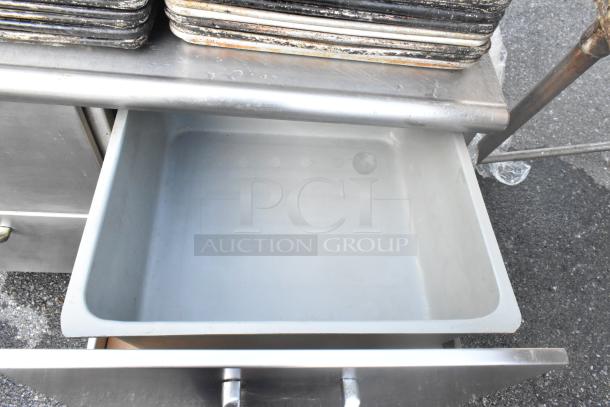 Stainless steel 4-drawer counter with open drawer. Features durable surface, ideal for professional kitchens. Good condition.