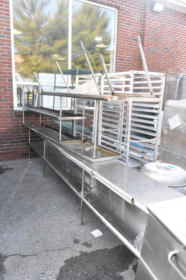 Three stainless steel over shelves, industrial design, on metal legs, in used condition, showing rust and wear.