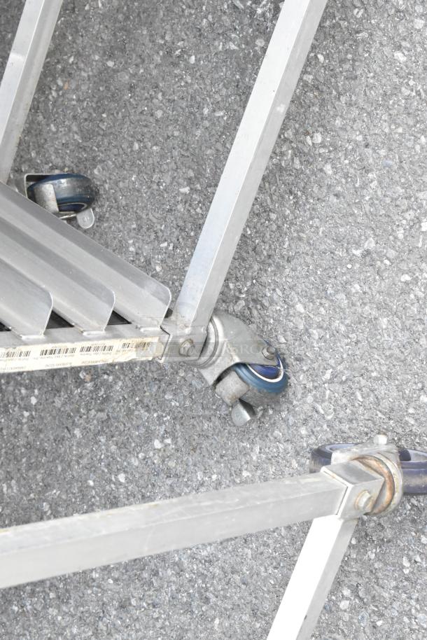 Metal commercial double pan transport rack with sturdy metal frame and commercial casters, slight wear visible.