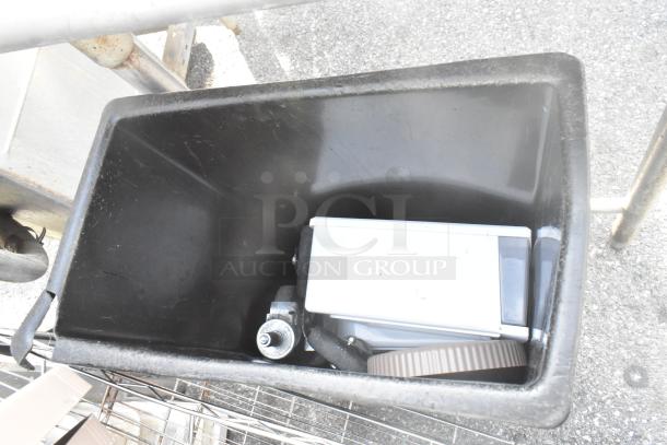 Black Slim Jim poly trash can with assorted contents; some wear visible on edges.