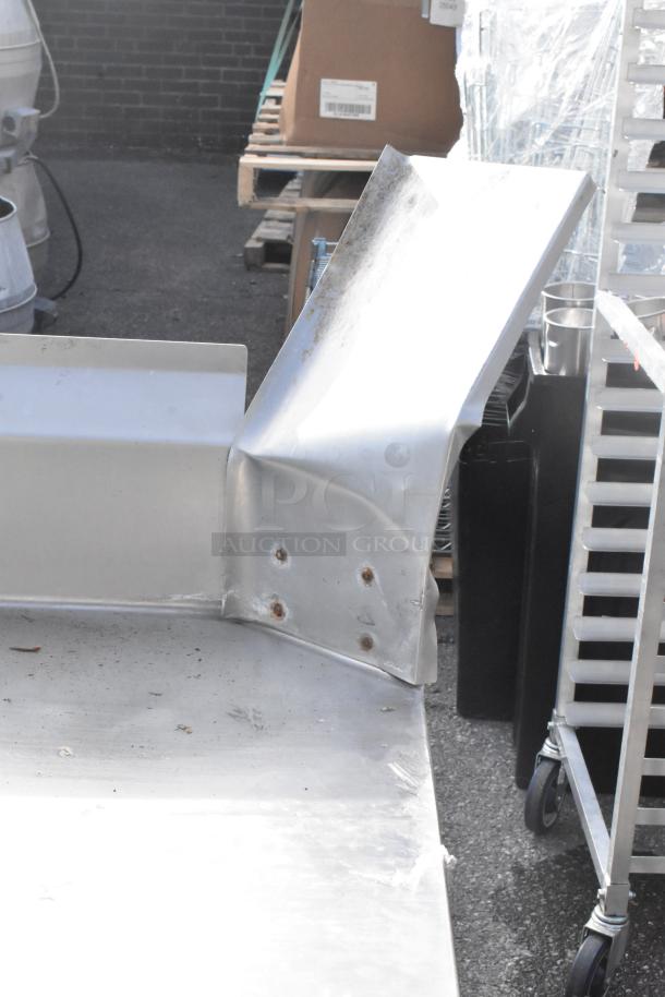 Stainless steel L-shaped dishwasher table, clean side, showing wear and rusted screws; ideal for commercial kitchens.